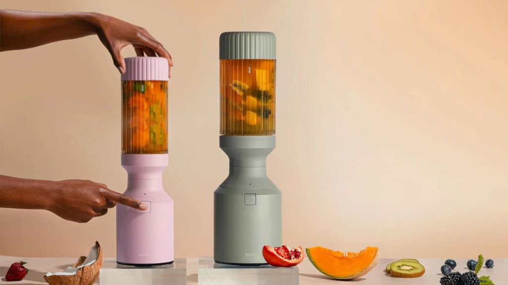 Portable blender making a fresh smoothie with fruit on a kitchen counter.
